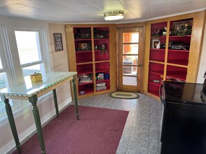 Cozy retreat with a glass-top table, woven rug, and a bookshelf filled with books and decorative items.