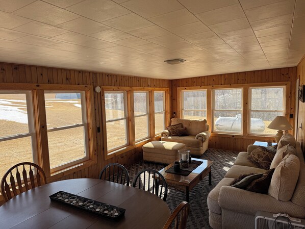 Relax in this inviting room with a large dining table, comfortable sofa, and stunning views of the outdoors.
