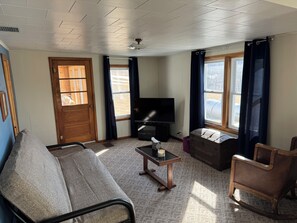 Relax in this stylish living room with a comfortable sofa, wooden rocking chair, and flat-screen TV.
