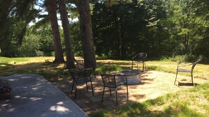 An outdoor seating area with metal chairs and a round table, surrounded by trees and grass. - Shady Pines Retreat  (Ontario)