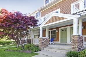 A two-story house with a front porch, a brick column, and a green door.