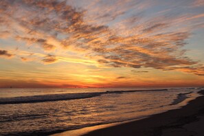 Une plage au coucher du soleil, avec des nuages.