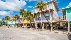 Un bien immobilier situé en bord de mer, avec une enseigne indiquant « Paradise Isle », comprenant un bâtiment à deux étages doté de balcons et d’un espace de stationnement.