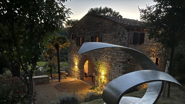 A rustic stone building with a modern metal sculpture in the foreground.
