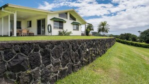 Une maison à deux étages, dotée d’un mur de soutènement en pierre, d’un porche couvert et d’une pelouse bien entretenue.