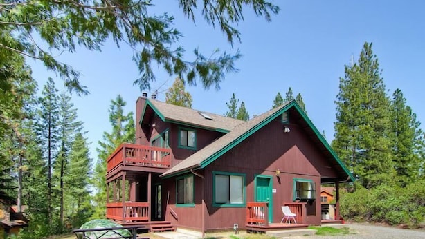 A two-story cabin with a balcony, a front porch, and a gravel driveway. - Yosemite Pines (Yosemite)