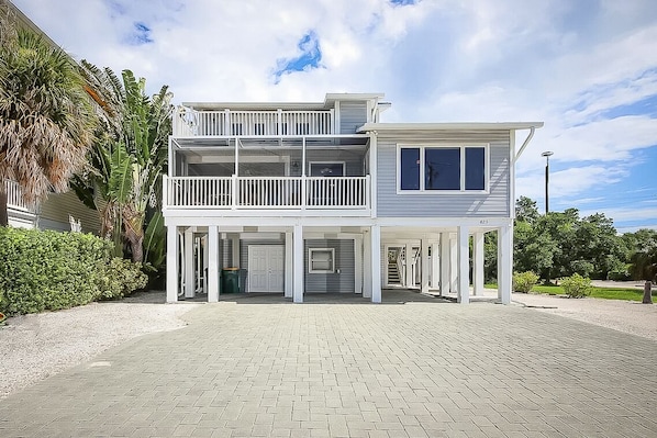 Une maison à deux étages avec un balcon, un garage et une véranda couverte.