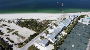 Vista aérea de un hotel costero con varias construcciones, un aparcamiento y una playa.
