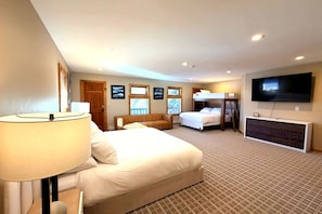 Une chambre d’hôtel avec un grand lit, un canapé, un bureau avec une télévision et une fenêtre donnant sur un beau paysage.