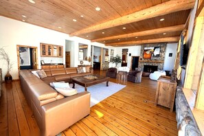 Un salon spacieux avec un grand canapé en cuir marron, un parquet en bois et une cheminée en pierre.