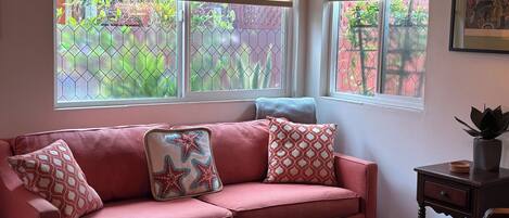 A room with a pink sofa, a wicker coffee table, and a small wooden side table.