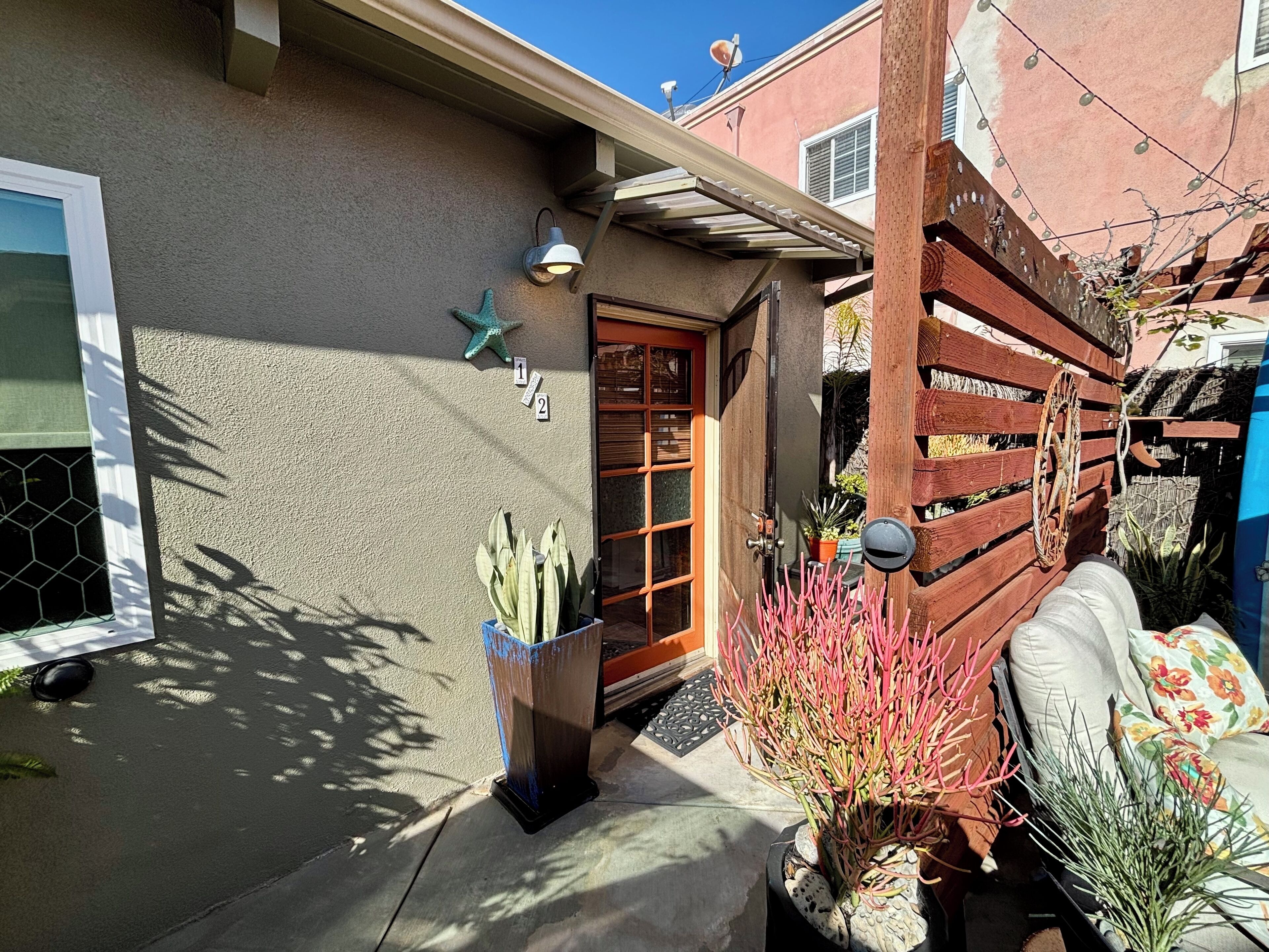A residential house with a wooden door, a starfish decoration, and a potted plant.