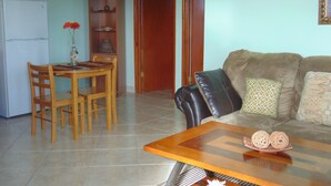 Un soggiorno con un tavolo da pranzo in legno, sedie, un divano e un tavolino.