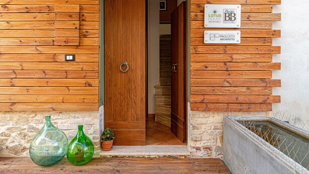 A wooden exterior with a door, two green glass bottles, and a small potted plant. - B&B Lotus House (Lanciano)