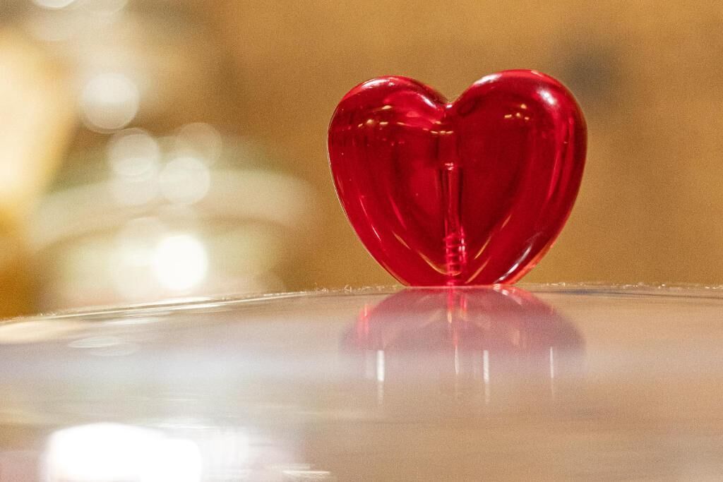 Un objeto rojo con forma de corazón sobre una superficie reflectante.