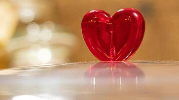 Un objeto rojo con forma de corazón sobre una superficie reflectante.