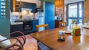 A modern kitchen with a dining area, featuring a wooden table, chairs, and a built-in oven. - B&B Lotus House (Lanciano)