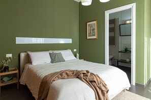 A bedroom with a bed, a nightstand, a framed picture, and a bathroom visible through an open door. - B&B Lotus House (Lanciano)