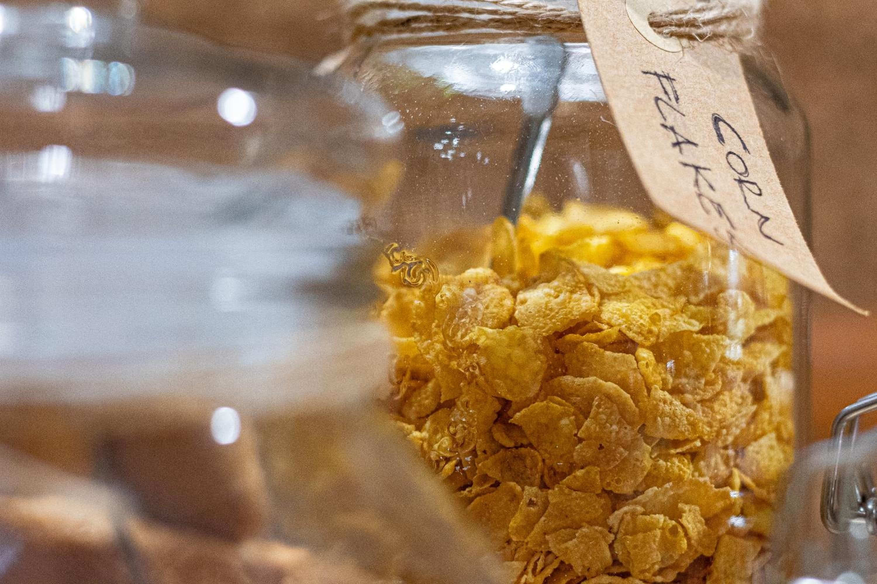 A glass jar with a metal clasp and a tag labeled 'corn flakes.'