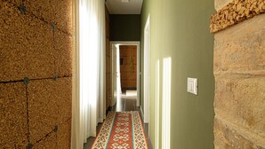 A hallway with a patterned carpet, a stone wall, and a door leading to another room. - B&B Lotus House (Lanciano)