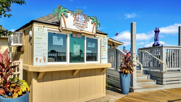 A small ice cream stand with a menu board, located on a wooden deck with a railing and potted plants. - Hilton Head Tennis Villa  (Hilton Head Island)