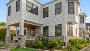 A two-story house with a covered porch, stone foundation, and a landscaped front yard. - 100 steps to Lake Michigan beach, private courtyard. Book Notre Dame wknds now! (Michigan City)