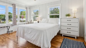 A bedroom with a bed, dresser, windows, and a view of greenery outside. - 100 steps to Lake Michigan beach, private courtyard. Book Notre Dame wknds now! (Michigan City)
