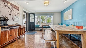 A modern kitchen with wooden cabinetry, a large wooden table, and a seating area with a bench. - 100 steps to Lake Michigan beach, private courtyard. Book Notre Dame wknds now! (Michigan City)