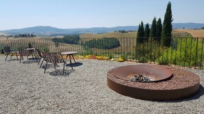 Une terrasse extérieure dotée d’un foyer, d’un espace salon et offrant une vue sur des collines ondoyantes et des montagnes lointaines.