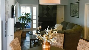 A dining area with wicker chairs, a round table, and a hanging light fixture.