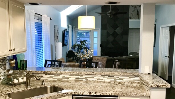 A modern kitchen with white cabinetry, a stainless steel dishwasher, and a granite countertop.