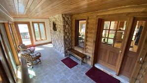 A wooden interior with a stone wall, a bench, and a door.