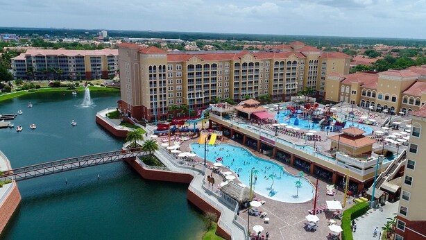 A resort with a large pool, water slides, and a bridge over a body of water.