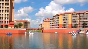 A waterfront hotel with multiple buildings, a canal with boats, and a clear sky.