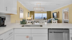 A modern kitchen with white cabinetry, a stainless steel dishwasher, and a large island with a sink.