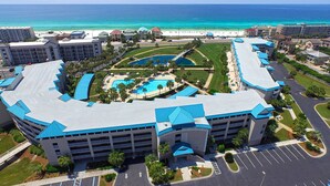 A hotel with a curved roof, multiple swimming pools, and a beach view.