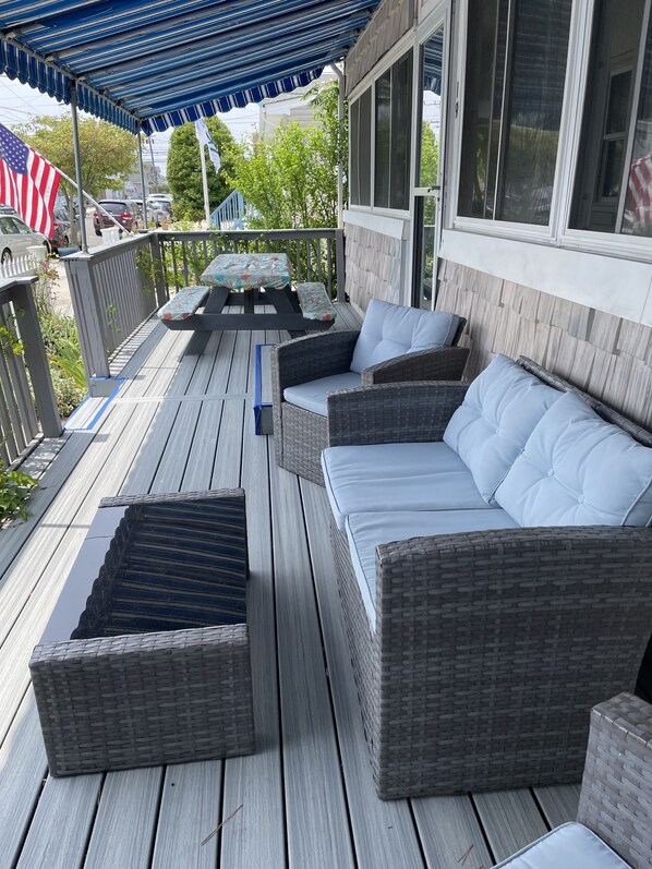 Relax on the covered deck with wicker furniture and a table for a peaceful retreat.