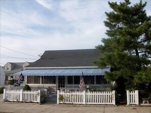 Stylish home with a symmetrical design, featuring a white picket fence and an American flag.