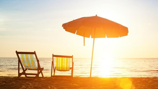 Une scène de plage avec deux chaises de plage et un grand parasol.