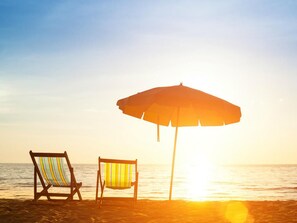 Une scène de plage avec deux chaises de plage et un grand parasol.