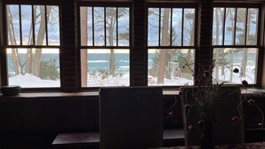 Quarto com uma grande janela com vista para uma paisagem nevada e para o oceano.