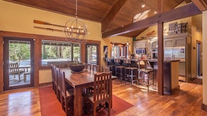 A spacious dining area with a wooden table and chairs, a large bowl centerpiece, and a view of the outdoors through large windows. - Perfect Family Getaway With A/C - Location! Location! (Homewood)