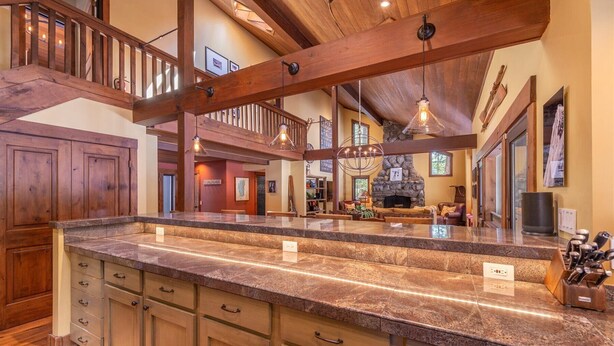 A spacious kitchen with a large island, wooden beams, and a stone fireplace. - Perfect Family Getaway With A/C - Location! Location! (Homewood)