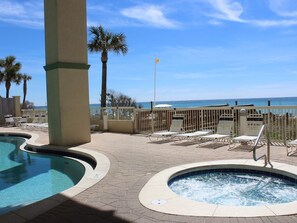 A pool area with a hot tub, lounge chairs, and a view of the ocean. - GULF FRONT *Renovated* 3 BR (2 King Suites) + Beach Chair Svc.  Owner Managed! (Panama City Beach)