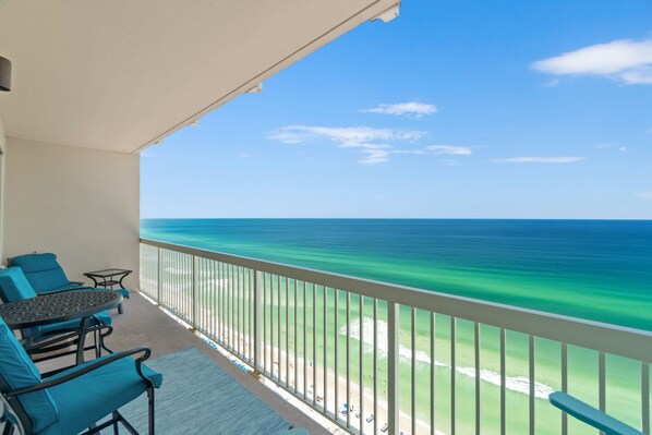 A balcony with a view of the ocean, a table, and blue chairs. - GULF FRONT *Renovated* 3 BR (2 King Suites) + Beach Chair Svc.  Owner Managed! (Panama City Beach)