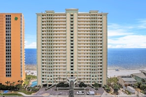 Un hôtel de grande hauteur doté de nombreux balcons, d’un atrium central et offrant une vue sur la plage.