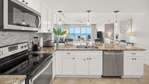 A modern kitchen with white cabinets, a stainless steel microwave, and a dishwasher. - Oceanfront Elegance, Great Views, on the beach, steps to the sand 2BR/2BA (Destin)