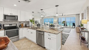 A modern kitchen with white cabinets, stainless steel appliances, and a large island. - Oceanfront Elegance, Great Views, on the beach, steps to the sand 2BR/2BA (Destin)