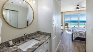 A bathroom with a marble sink, a large mirror, and a ceiling fan. - Oceanfront Elegance, Great Views, on the beach, steps to the sand 2BR/2BA (Destin)