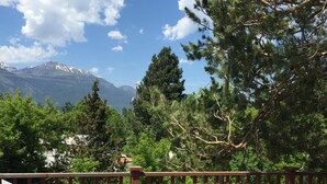 Eine Terrasse mit zwei gepolsterten Stühlen und einem kleinen Tisch, mit Blick auf eine gebirgige Landschaft.